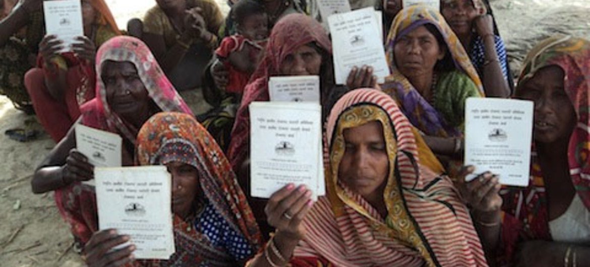 Des femmes Dalit, aux abords du village de Chakrapanpur, dans le district de Varanassi, brandissent leurs cartes de travail.