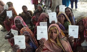 Dalit Women on the outskirts of Chakrapanpur Village, Varanasi District, Uttar Pradesh, display  job cards.