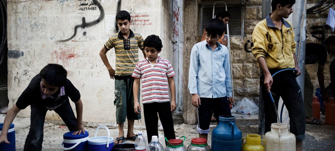 أطفال يصطفون لملء صفائح المياه وغيرها من الأدوات بالماء في حلب التي كانت مسرحا لقتال لفترة طويلة أثناء الصراع. ©صورة اليونيسف