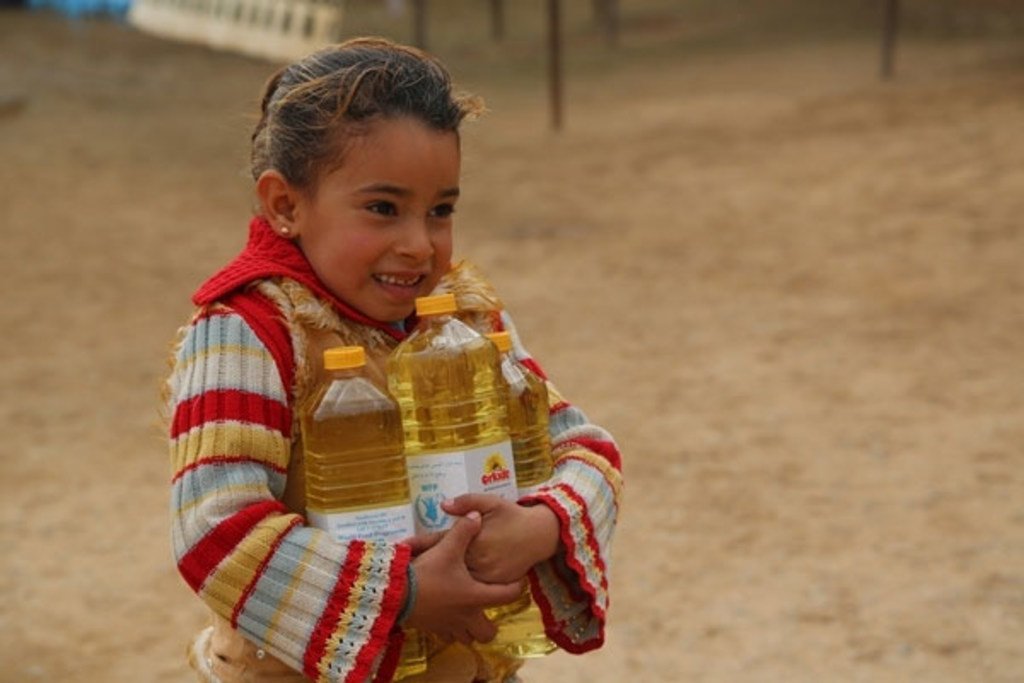 Une petite syrienne porte des bouteilles d'huile fournies par le PAM. Photo: PAM/Abeer Etefa