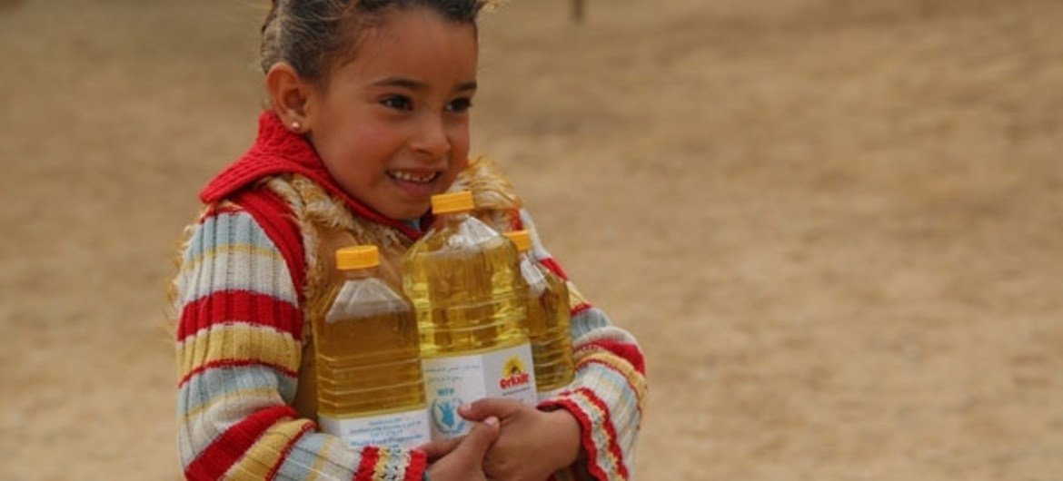 Sarah, age 7, carries vegetable oil, part of her family’s food allowance.
