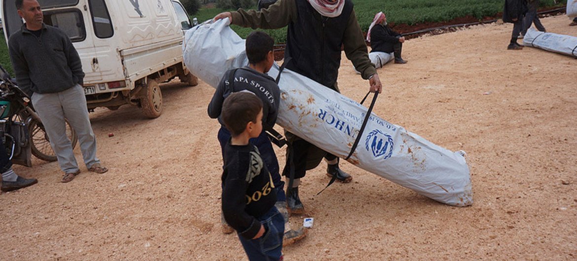 A father and his sons carry away their new family tent in Kerama Camp, northern Syria, close to Bab Al-Hawa border crossing.