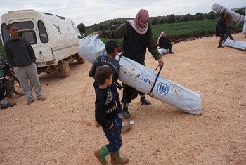 A father and his sons carry away their new family tent in Kerama Camp, northern Syria, close to Bab Al-Hawa border crossing.