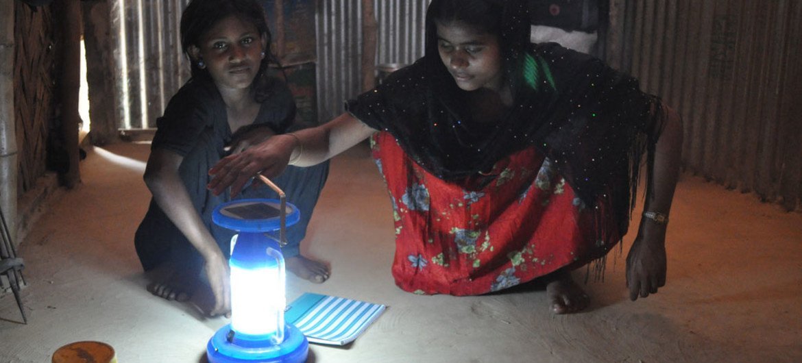 Une réfugiée et sa fille se servent d'une lampe solaire.