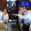 Secretary-General Ban Ki-moon (left) chats with Ray Chambers,  Special Envoy for Malaria, during a flight to Thailand (Nov 2011).