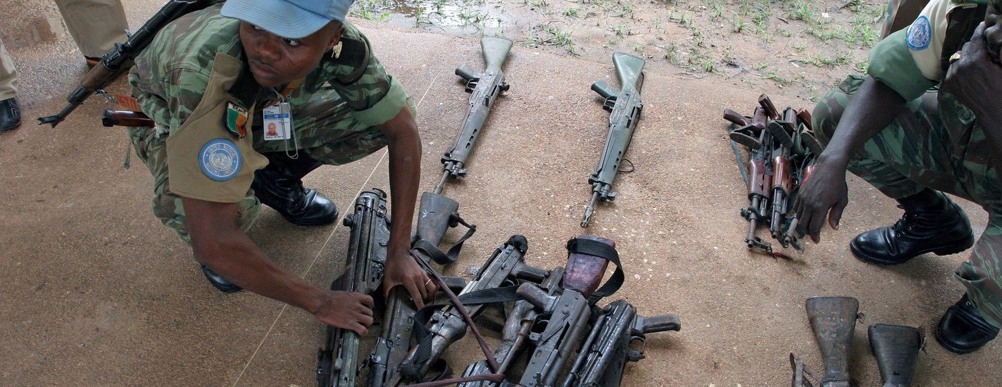 A UN peacekeeper with weapons obtained from militiamen in Côte d'Ivoire. 