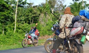 Passers-by on a motorcycle wave to ‘dozos’ posted along the road between Man and Duékoué in western Côte d’Ivoire.