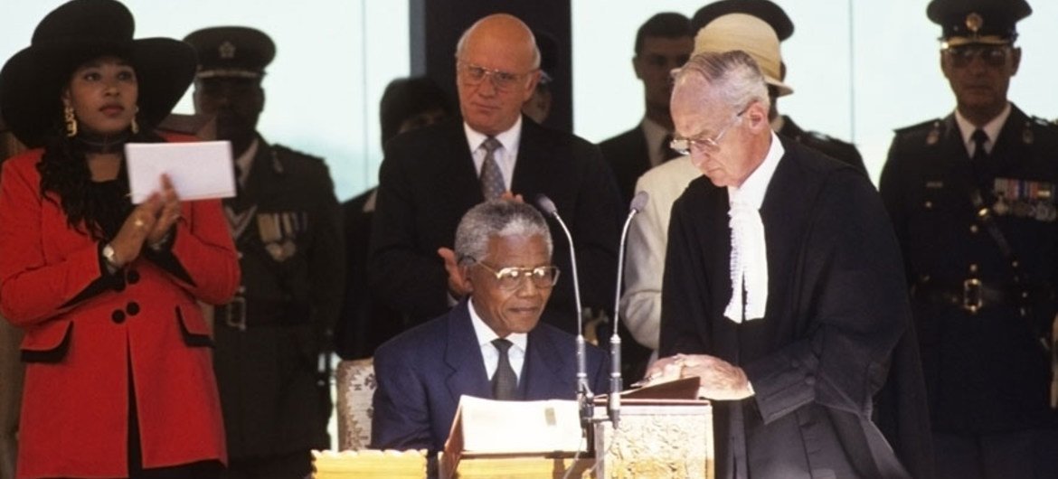 Nelson Mandela (sentado al centro) firma el acta para asumir el cargo de presidente de Sudáfrica en 1994.