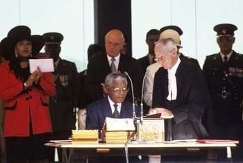 President Nelson Mandela (seated) signs the oath of office, as he assumes the Presidency of South Africa in 1994. UN Photo/C Sattleberger