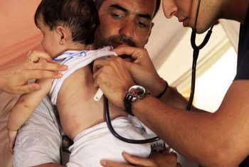 Un père syrien porte sa petite fille qui est examinée par un médecin en Turquie.