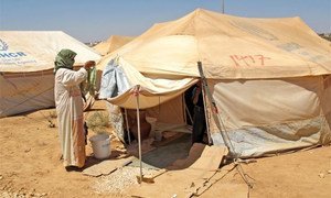 Une réfugiée syrienne  suspend son linge devant sa tente dans le camp de Za'atari en Jordanie