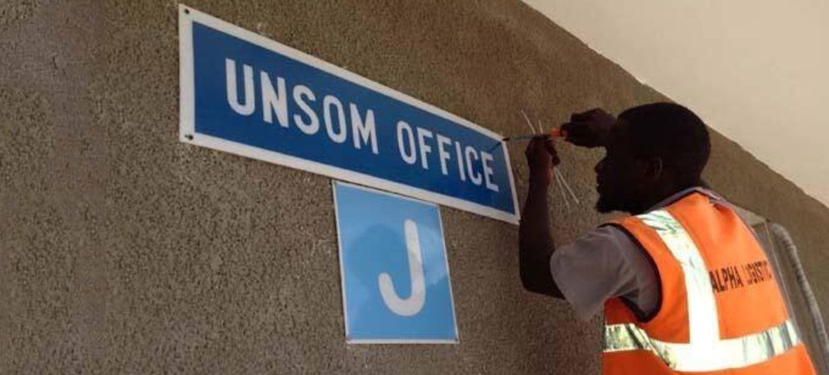 Un homme installe une pancarte au bureau de la MANUSOM à Mogadiscio.