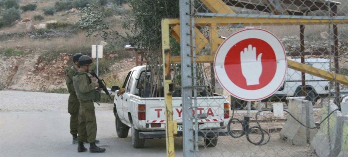 Israeli soldiers inspect a vehicle entering the village of Azzun Atma through the West Bank Barrier.