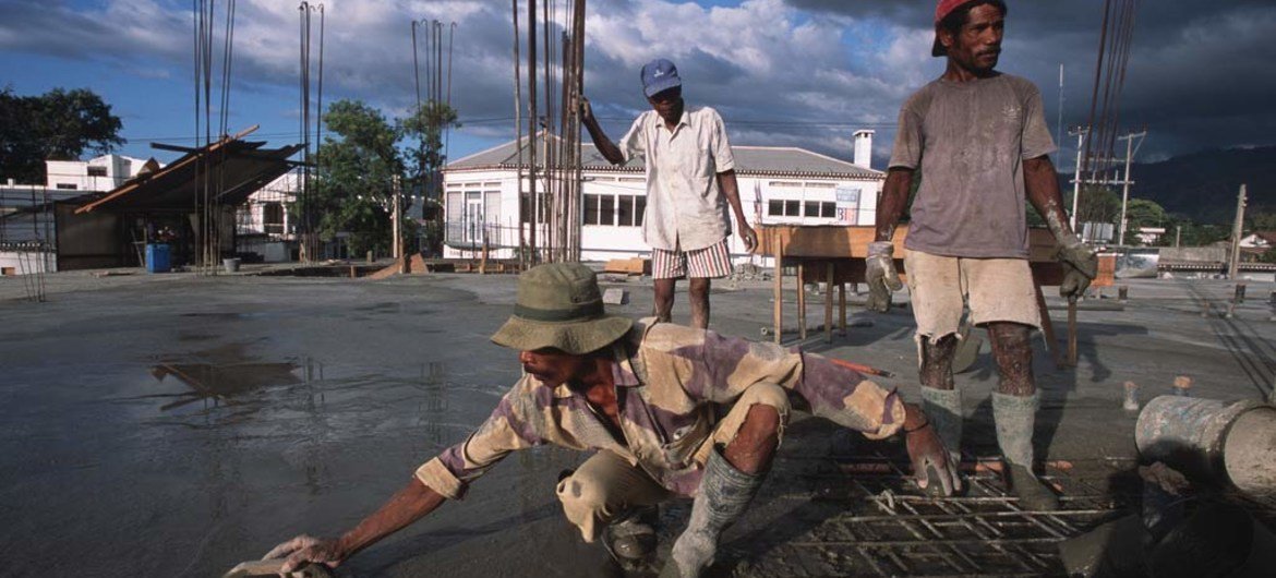 Men at work pouring cement on a rooftop.
