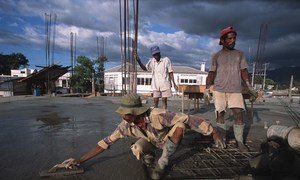 Men at work pouring cement on a rooftop.