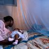 Infant surrounded by protective malaria bed net in Ghana.