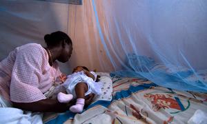 Infant surrounded by protective malaria bed net in Ghana.