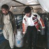 En Afghanistan, des travailleurs laitiers transportent un bidon de lait en Afghanistan.
