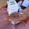 Au Lesotho, une femme tient dans sa main un médicament de traitement antirétroviral contre le sida pour sa petite-fille.