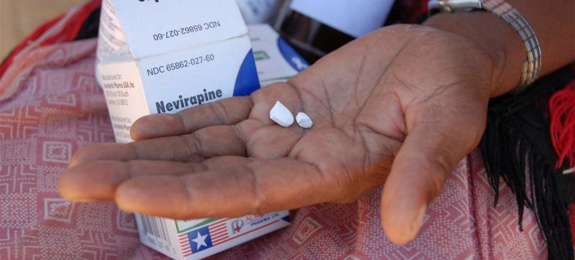 Au Lesotho, une femme tient dans sa main un médicament de traitement antirétroviral contre le sida pour sa petite-fille.