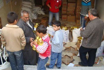 Families collect their food rations at a distribution point in Tartous, a port city in western Syria.