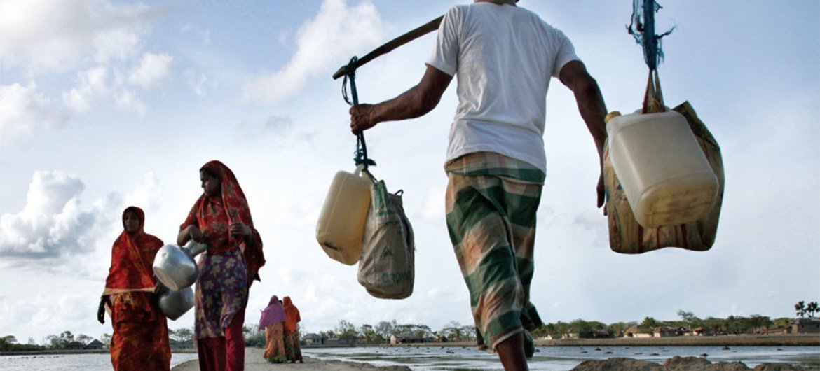 Above, people carry drinking water in Bangladesh.