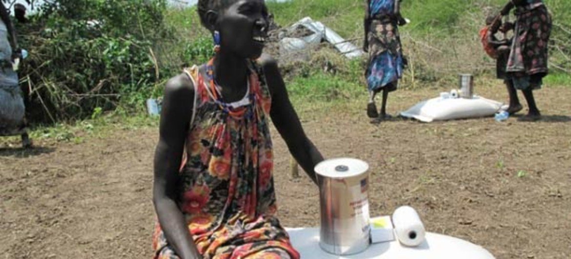 A woman in Dorein, South Sudan, sits next to food assistance she has just received from WFP for her family.