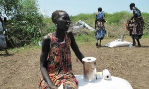 A woman in Dorein, South Sudan, sits next to food assistance she has just received from WFP for her family.