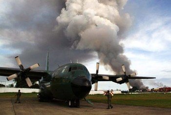 Black smoke from burning houses rises in the background as a military cargo plane bearing relief goods arrives in the besieged city of Zamboanga in Mindanao, Philippines on 12 September 2013.