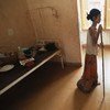 A woman suffering from HIV/AIDS in Cambodia uses a stick to walk back to her bed in hospital.