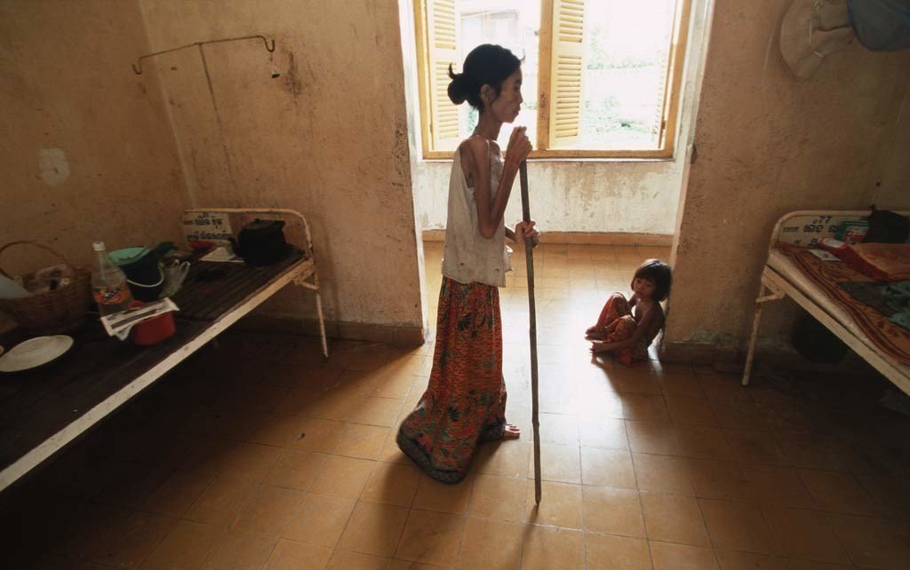 Au Cambodge, une femme atteinte du VIH/sida s'aide d'une canne pour s'approcher de son lit d'hôpital.