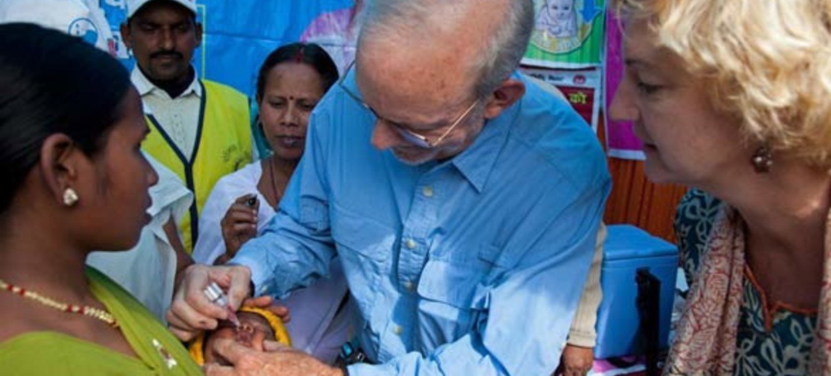 UNICEF Executive Director Anthony Lake (centre) administers an oral polio vaccine to a child at  in Bihar State, India.