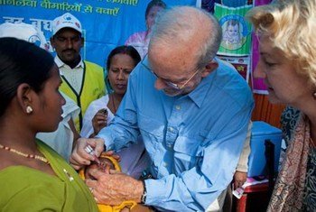 UNICEF Executive Director Anthony Lake (centre) administers an oral polio vaccine to a child at  in Bihar State, India.