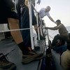 Des garde-côtes italiens aident un groupe de migrants à bord d'une embarcation bondée, près de l'île italienne de Lampedusa.