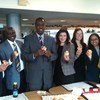 Sept collègues, assis dans un bureau, sourient en tenant des cupcakes.