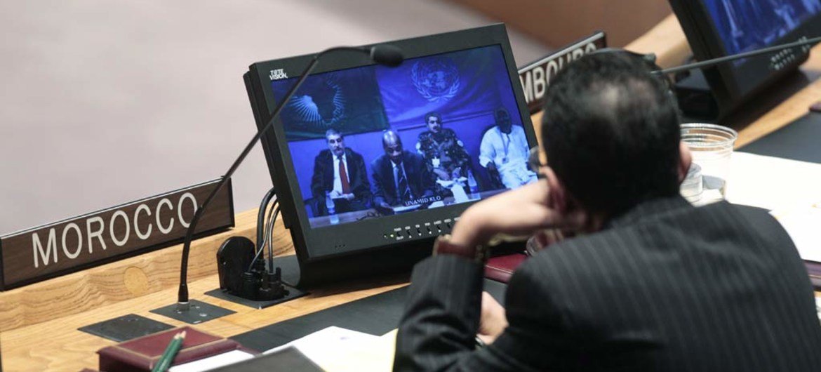 A Security Council delegate watches on video screen Mohamed Ibn Chambas, Joint Special Representative and head of UNAMID, addressing the Council via video conference.