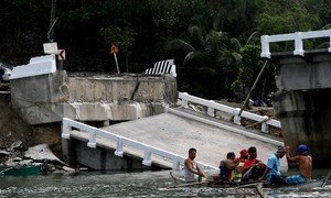Survivors of a 7.2 magnitude killer quake that struck the central Philippines use a small canoe to cross a river after the main bridge connecting the hardest hit town of Loon in Bohol.