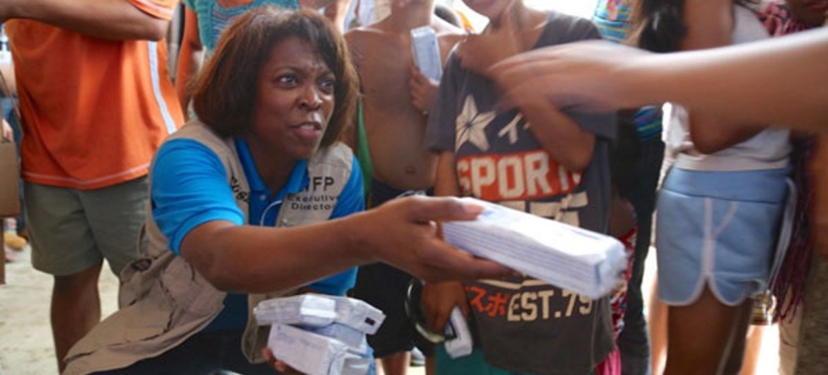 WFP Executive Director Ertharin Cousin (left) helping to distribute biscuits to children at an evacuation centre in Tacloban, the Philippines.