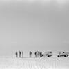 A black and white photograph shows a group of men standing next to white UN vehicles in a vast desert landscape.