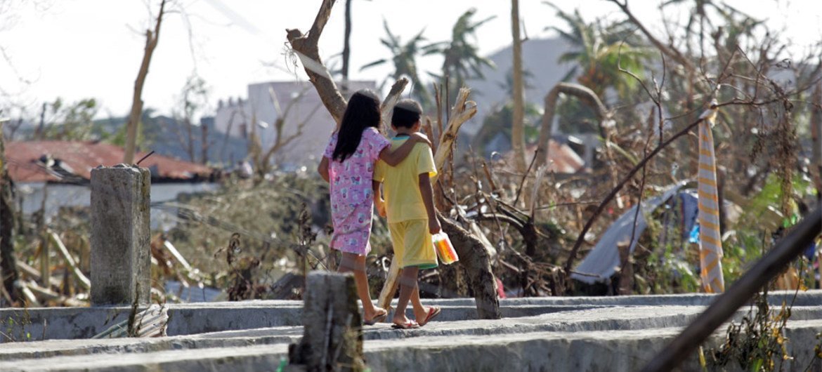 Two children walk past downed trees and other destruction caused by Super Typhoon Haiyan in Tacloban City.