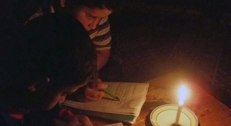 Dos niños leen alumbrados por una vela en Gaza