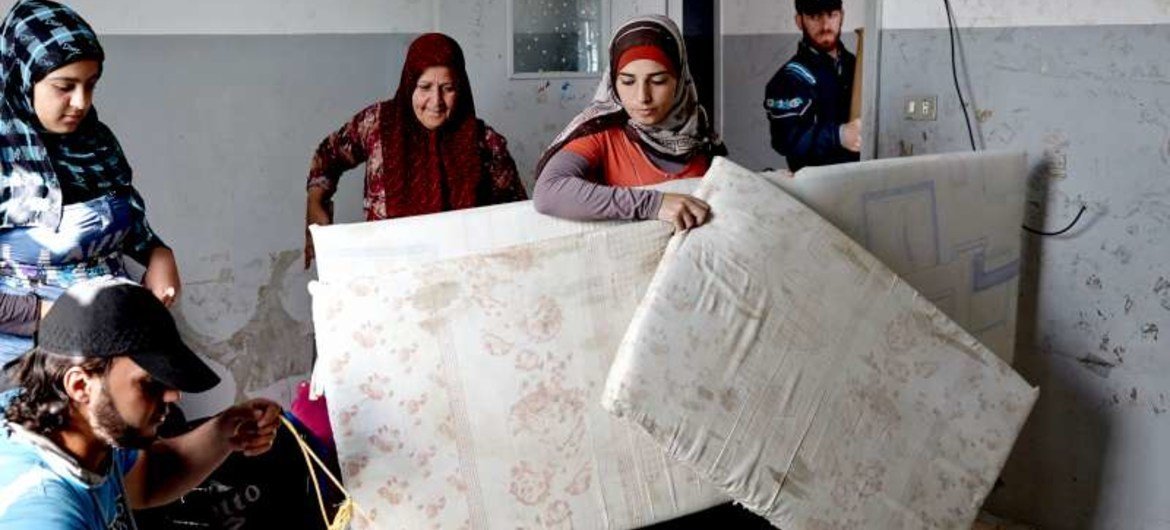 A group of Syrian refugee women move into their new home, a former chicken farm, near Qoubaiyat, Lebanon.