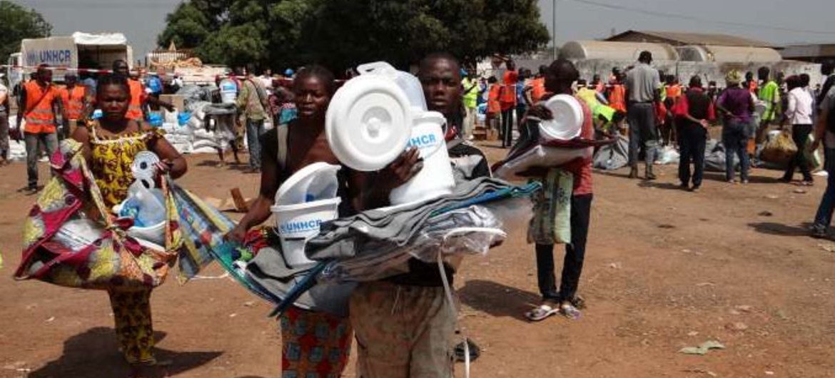 Displaced families carry aid received at a distribution organized by UNHCR and WFP at the Bangui airport site.