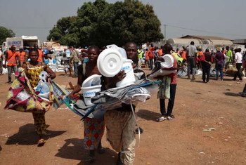 Displaced families carry aid received at a distribution organized by UNHCR and WFP at the Bangui airport site.
