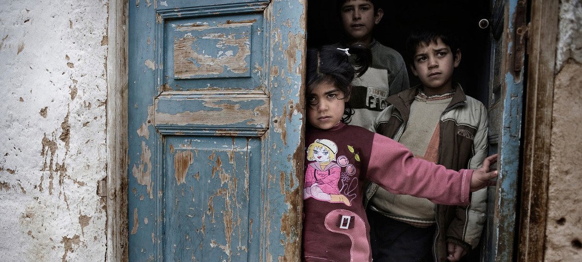 在受冲突影响的城市，叙利亚儿童在炮火和炮击中躲藏在房屋的门口。