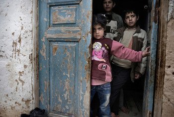 Syrian children shelter in the doorway of a house, amid gunfire and shelling, in a city affected by the conflict.