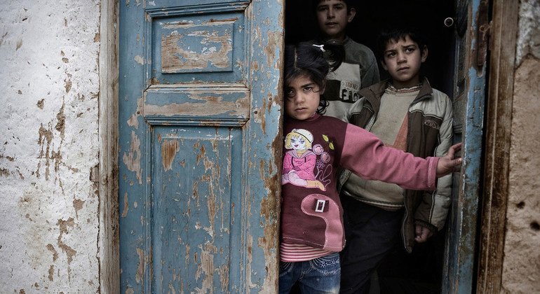 Niños sirios se refugian de las bombas y disparos en el portal de una casa