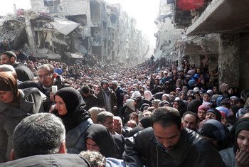 Yarmouk residents gather to await food distribution from UNRWA in January 2014.