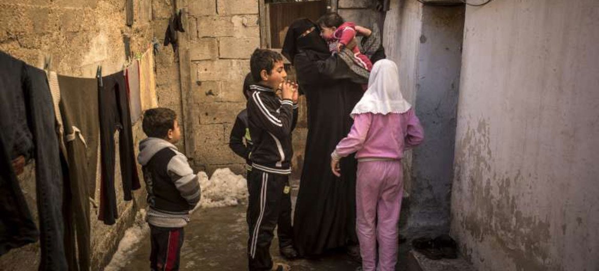 A Syrian mother and her children arrive at the dilapidated basement building where they are staying in Amman, the capital of Jordan.