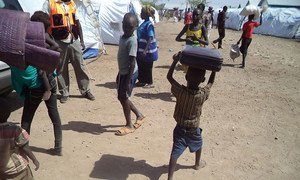 A barefooted little boy who has just arrived in Kakuma refugee camp, north-western Kenya, from South Sudan, runs with a suitcase on his head, trying to keep up with registration procedures.